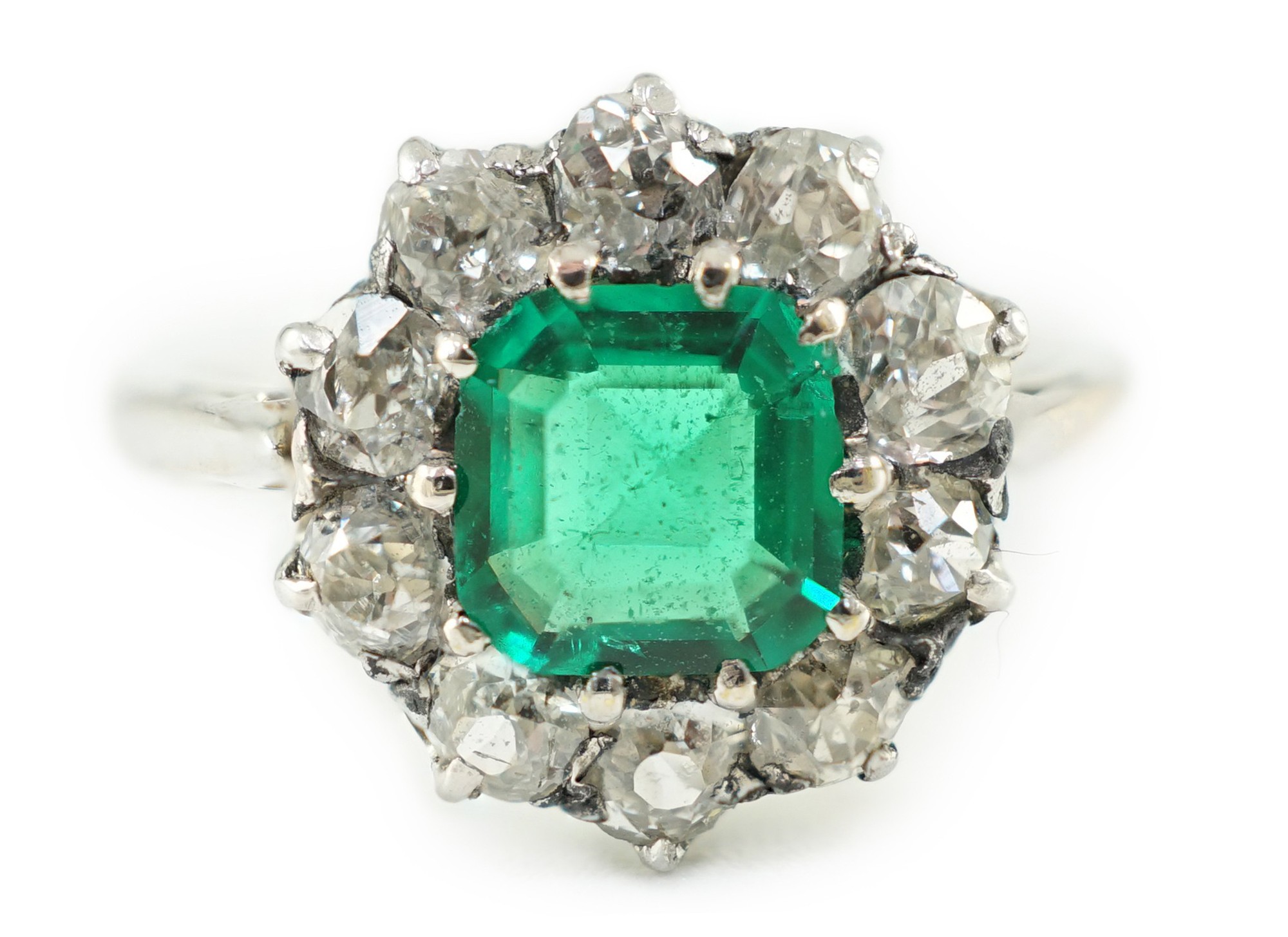 An early to mid 20th century, platinum, octagonal cut emerald and round cut diamond set circular cluster ring